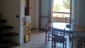 Ein Zimmer mit Esstisch, Stühlen, einem Schrank und einer Heizung.