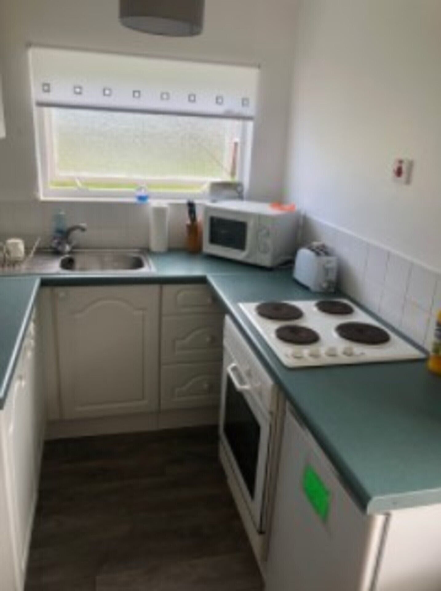 A compact kitchen with a sink, microwave, toaster, and stove.
