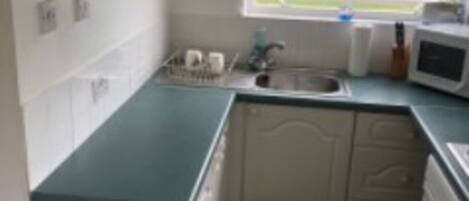 A compact kitchen with white cabinets, a microwave, and a sink.