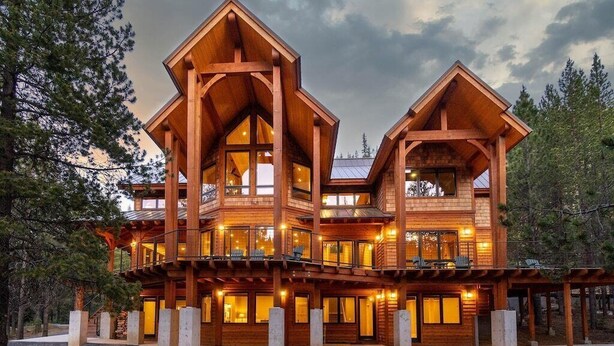 A large, multi-story wooden cabin with multiple balconies and large windows, surrounded by trees. - Spectacular Luxury Lodge Home w/Hot Tub, Sauna on Private Lake Sleeps 16-20 Bend (Bend)