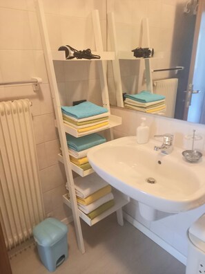 Ein Badezimmer mit weißem Waschbecken, einem Spiegel, einem Handtuchhalter und einer Heizung.