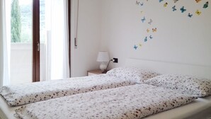 Een kamer met twee bedden, een nachtkastje, een lamp en vlinderstickers op de muur.
