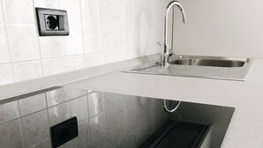 Een moderne keuken met een roestvrijstalen spoelbak, een inbouwvaatwasser en een zwart bedieningspaneel met rode knoppen.