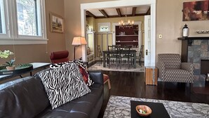 A spacious living room with a leather sofa, a patterned rug, and a dining area in the background.