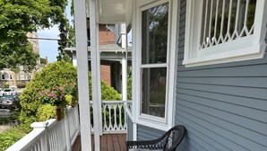 A wooden deck with two wicker chairs and a potted plant with pink flowers.