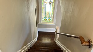 A wooden staircase with white trim and a handrail, leading to a room with a window and a door.