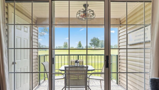 A view through a screened door onto a balcony with a table and chairs, a hanging light fixture, and a sign with a message. - Clean & Spacious 2BR/2BA.  Gated resort with amenities (Branson)