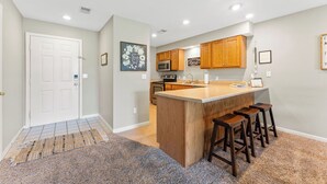 A kitchen with wooden cabinets, a central island with stools, and a microwave. - Clean & Spacious 2BR/2BA.  Gated resort with amenities (Branson)