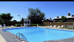 A rectangular swimming pool with a clear blue water surface, surrounded by a tiled deck. - Clean & Spacious 2BR/2BA.  Gated resort with amenities (Branson)
