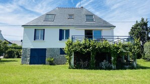 A two-story house with a sloped roof, a small porch with a stone wall, and a blue door. - CARNAC House 5 rooms - 8/10 persons - Wifi (CARNAC)