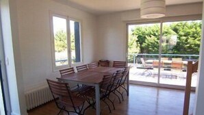 A dining area with a large table and chairs, large windows, and a view of outdoor seating. - CARNAC House 5 rooms - 8/10 persons - Wifi (CARNAC)