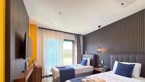 Une chambre d’hôtel moderne avec deux lits, un téléviseur à écran plat, une table de chevet avec une lampe et une vue sur l’extérieur.
