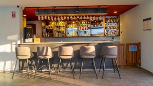 Un espace bar avec un comptoir, de nombreux tabourets et une variété de bouteilles et de verres.
