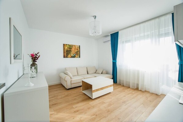A modern living room with a sofa, coffee table, and a painting on the wall. - Fantastic Apartment at Prima Residence (Oradea)