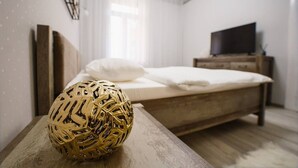 Une chambre à coucher avec un lit en bois, un téléviseur posé sur une commode en bois et un objet décoratif doré sur une table.