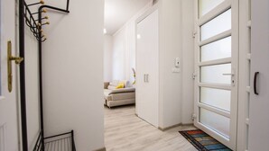 Un couloir avec une porte blanche, un porte-manteau et un canapé au fond.