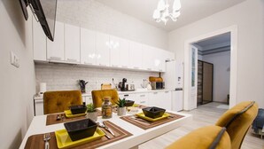 Une cuisine moderne avec des meubles blancs, une table à manger agrémentée de sets de table jaunes et de bols noirs, et une chaise jaune.