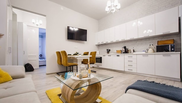 Un salon moderne avec une table basse en verre, des canapés blancs et un coin repas comprenant une table et des chaises.