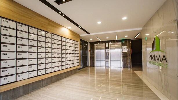 A modern hotel lobby with a marble floor, a wall of numbered room signs, and an elevator. - Bright & Elegant Central Apartment (Oradea)