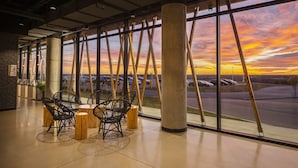 A modern interior with large windows, black woven chairs, and a view of a parking lot during sunset. - Dakota Dunes Resort (Whitecap)