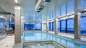 An indoor swimming pool with clear views of a snowy landscape through large windows. - Dakota Dunes Resort (Whitecap)