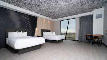 Una habitación de hotel moderna con dos camas, una zona de comedor y un ventanal con vistas.