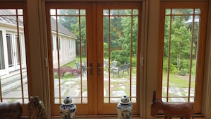 A view through a set of glass doors leading to a garden with outdoor furniture and a statue of a horse. - Candy Cove 
Peace and seclusion by the Sea in Maine (Saint George)