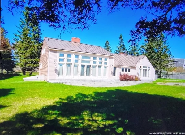 A modern two-story building with a flat roof, large windows, and a well-maintained lawn.