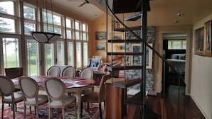 A dining area with a large table, chairs, and a hanging light fixture. - Candy Cove 
Peace and seclusion by the Sea in Maine (Saint George)