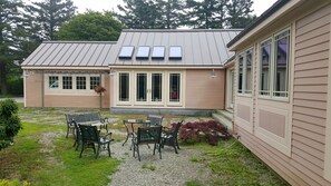 Una casa de dos pisos con un patio amueblado y un pequeño jardín.