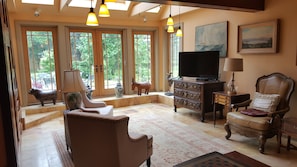 Relax in a spacious living room with a sofa, armchairs, and a TV on a cabinet.