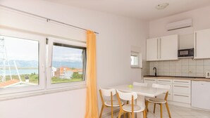 Une cuisine moderne avec des meubles blancs, une table à manger avec des chaises et une vue sur l’extérieur.