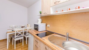 Une cuisine compacte avec des meubles en bois, un four à micro-ondes encastré, un évier et un coin repas avec des chaises.