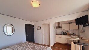 Ein gemütlicher Raum mit Bett, einer kleinen Küchenzeile, einem Essbereich und einem an der Wand montierten Fernseher.