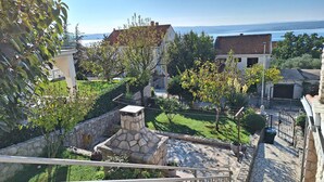 Ein Wohngebiet mit gepflasterten Wegen, einem Steinfbrunnen und Blick auf das Meer.