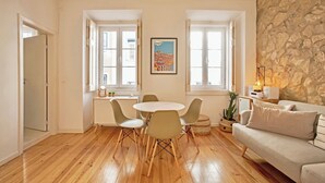 Ein Wohnzimmer mit Steinwand, einem runden Tisch mit Stühlen, einer Couch und einem Fenster mit Blick auf die Stadt.