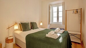 Ein Hotelzimmer mit Bett, Fenster, Nachttisch mit Lampe und Handtuchhalter.