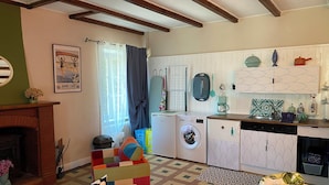 Un espacio habitable compacto con chimenea, un sofá multifuncional, lavadora y kitchenette.