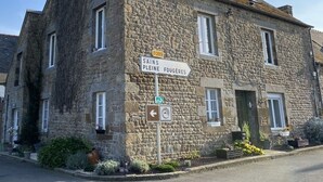 Un edificio de piedra con un cartel que indica las direcciones a Sains y Pleine Fougeres.