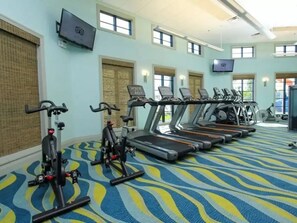 Un gimnasio con bicicletas estáticas, cintas de correr y equipo de ejercicio.