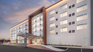 A modern hotel with a flat facade, multiple windows, and a covered entrance.