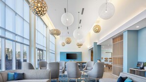 A spacious lobby with modern seating, large windows, and decorative hanging lights.