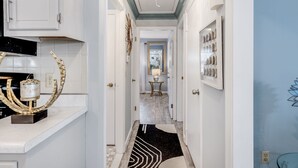 A hallway with a black and white rug, a mirror, and a decorative wall piece. - Charming Ranch on the Cape (Barnstable)