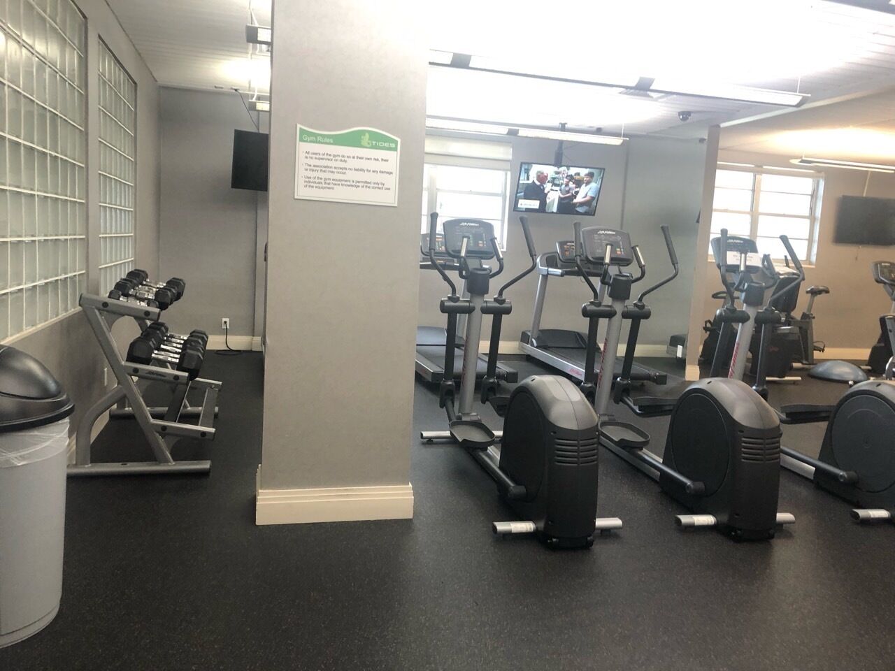 Une salle de sport équipée de divers appareils d’exercice, notamment des tapis de course, des vélos elliptiques et des bancs de musculation.