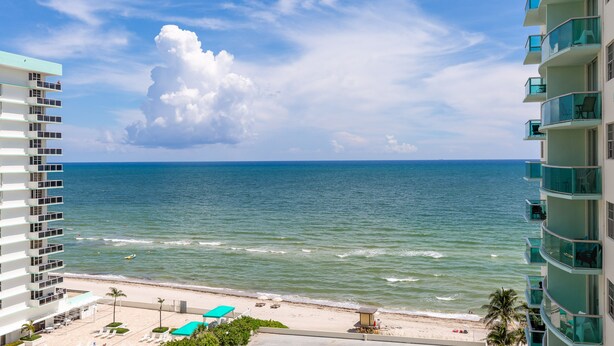 A beachfront hotel with balconies overlooking the ocean, a sandy beach, and a clear sky. - The Tides Ocean Luxury Suites (Hollywood)