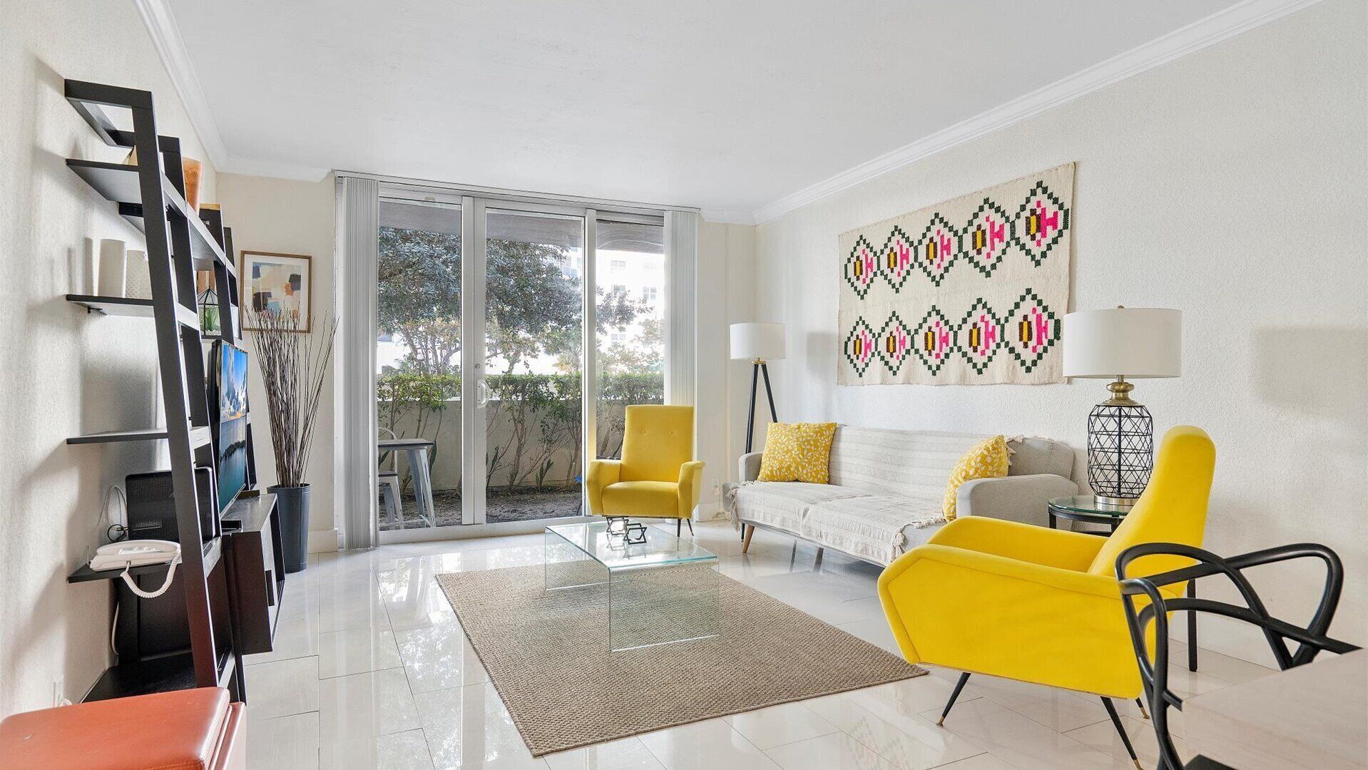 Una sala de estar moderna con un sofá, sillones amarillos, una mesa de centro de vidrio y un ventanal grande.