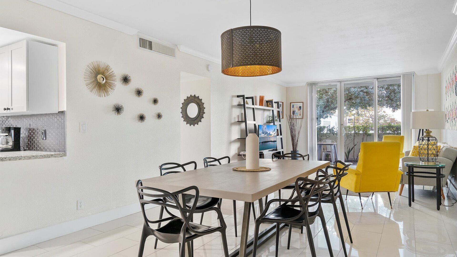 A modern dining area with a wooden table, black chairs, and a hanging light fixture.
