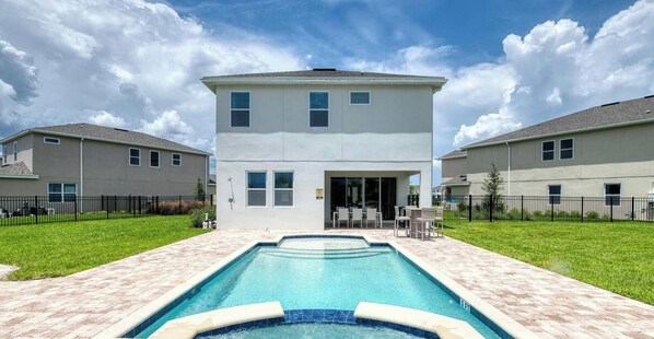 Un immeuble résidentiel de deux étages, avec une piscine en premier plan.