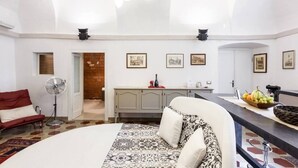 A spacious room with a large bed, a desk, a chair, and a dining area.