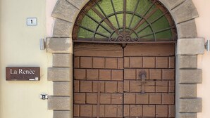 A double wooden door with a stone archway, a green glass window above, and a sign reading 'La Renée'.